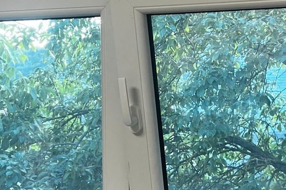 Maner alb de fereastra termopan PVC, prins in cremonul din cercevea, fotografiat de aproape