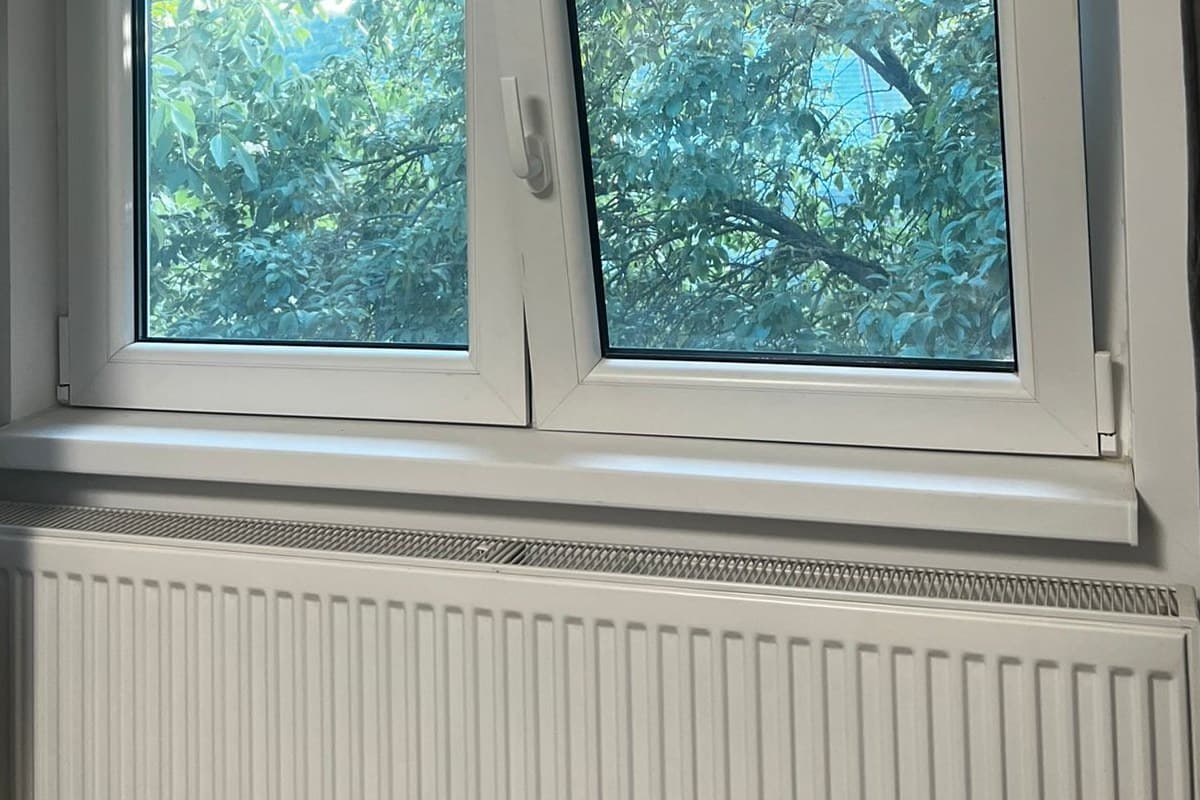 Pervaz interior alb de fereastra termopan PVC, cu caloriferul montat dedesubt, fotografiat din camera