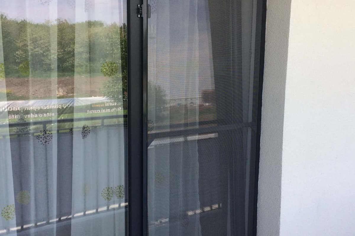 Plasa de tantari pe rama antracit, montata pe o usa de balcon si vazuta dinspre balcon